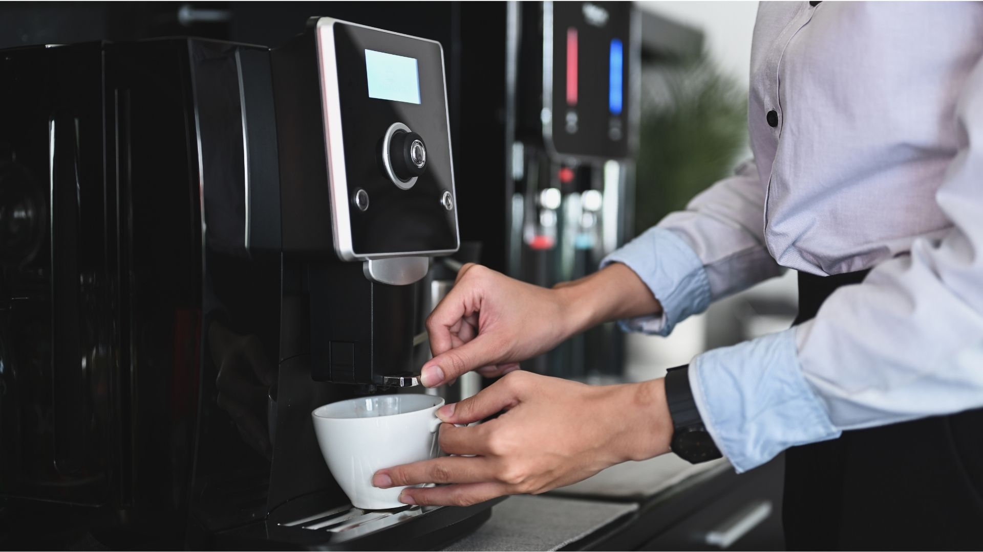 Man fills up coffee at a bean to cup machine in an office.